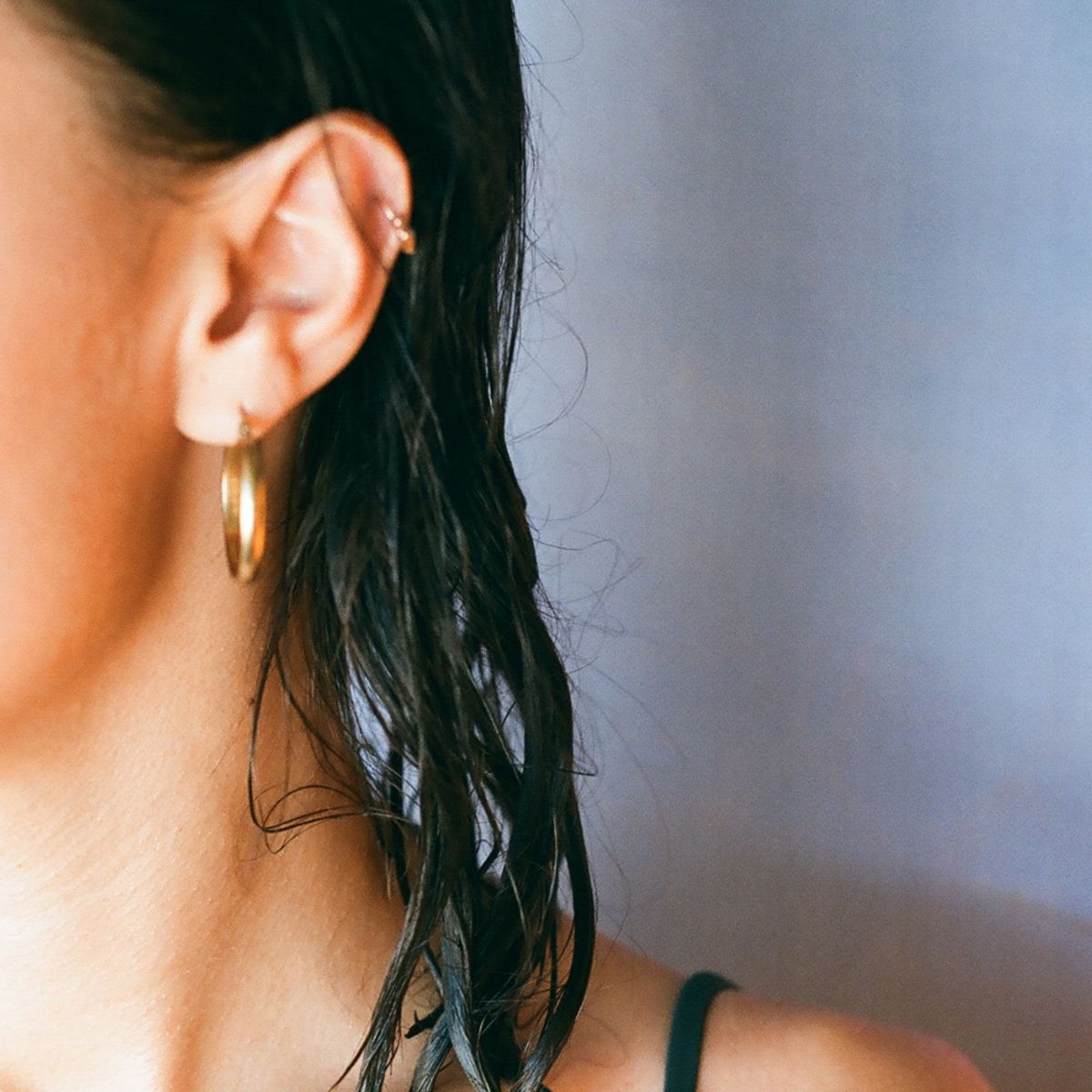 A girl with wet hair and wearing a gold hoop