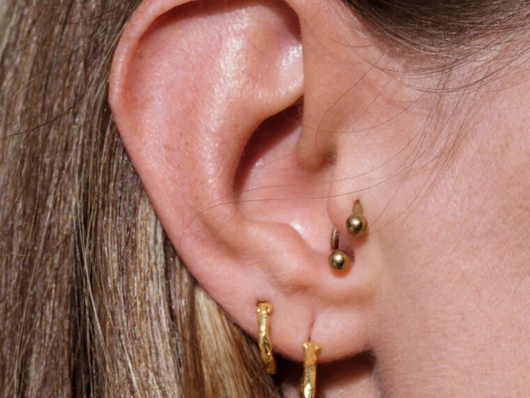 A girl with several earrings in her ear piercings.