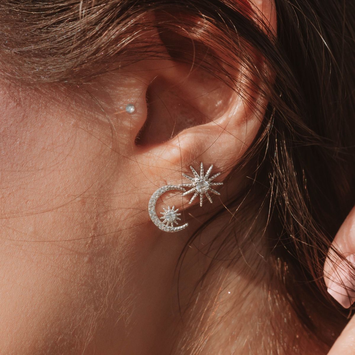 A girl wearing celestial themed silver earrings